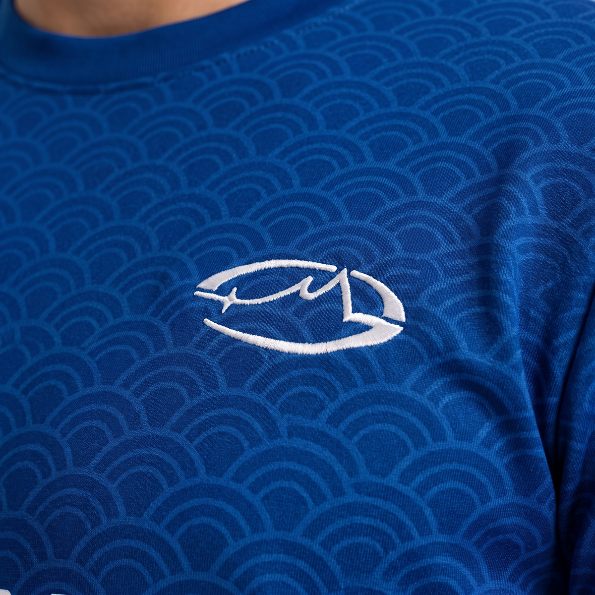 Gros plan créatif du logo brodé blanc sur le maillot bleu STRATO